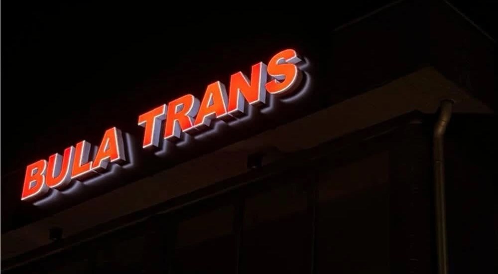 Illuminated 3D lettering “BULA TRANS” at night