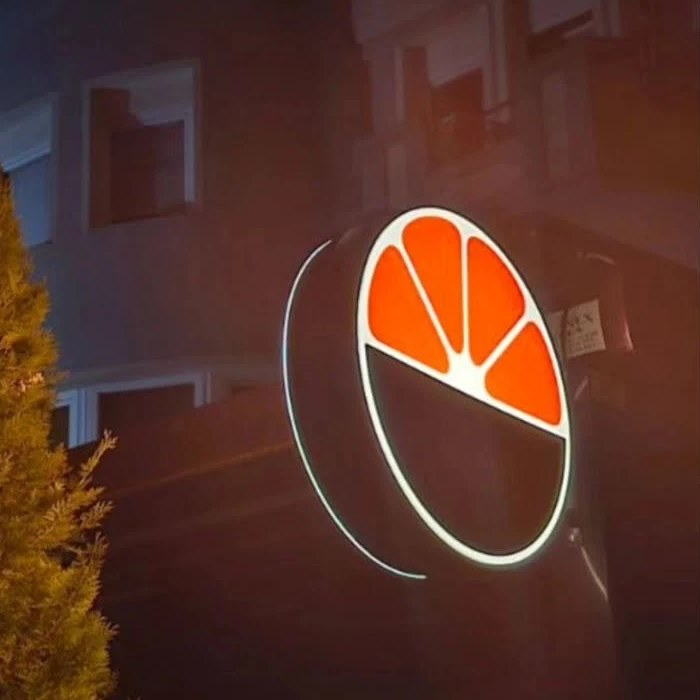 Illuminated round sign for M House at night